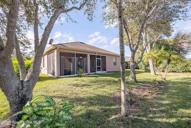 rear view of house with a lawn and a sunroom