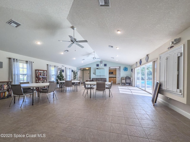 dining space with a textured ceiling, ceiling fan, tile patterned floors, and lofted ceiling