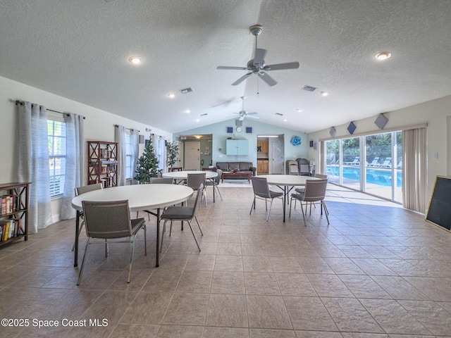 tiled dining space featuring ceiling fan, a textured ceiling, a wealth of natural light, and vaulted ceiling