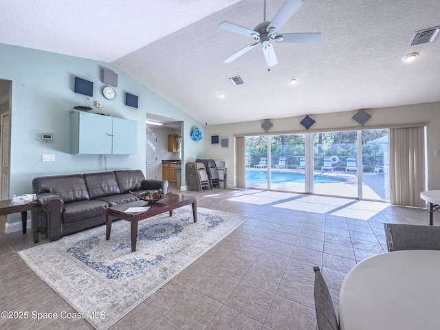 living room with a textured ceiling, ceiling fan, tile patterned flooring, and vaulted ceiling