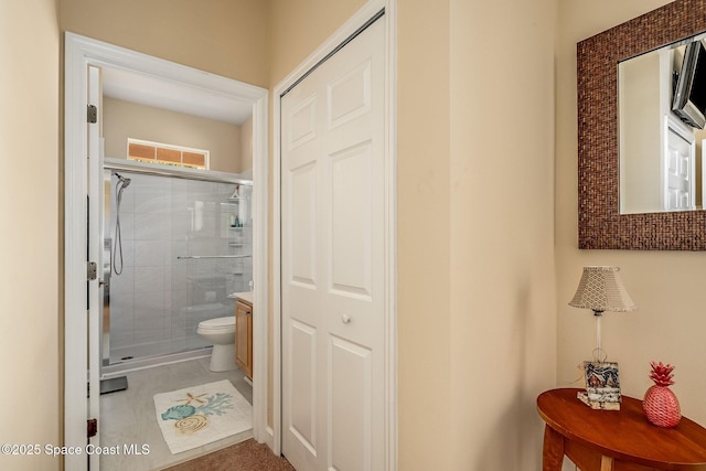 bathroom with tile patterned floors, vanity, toilet, and a shower with door