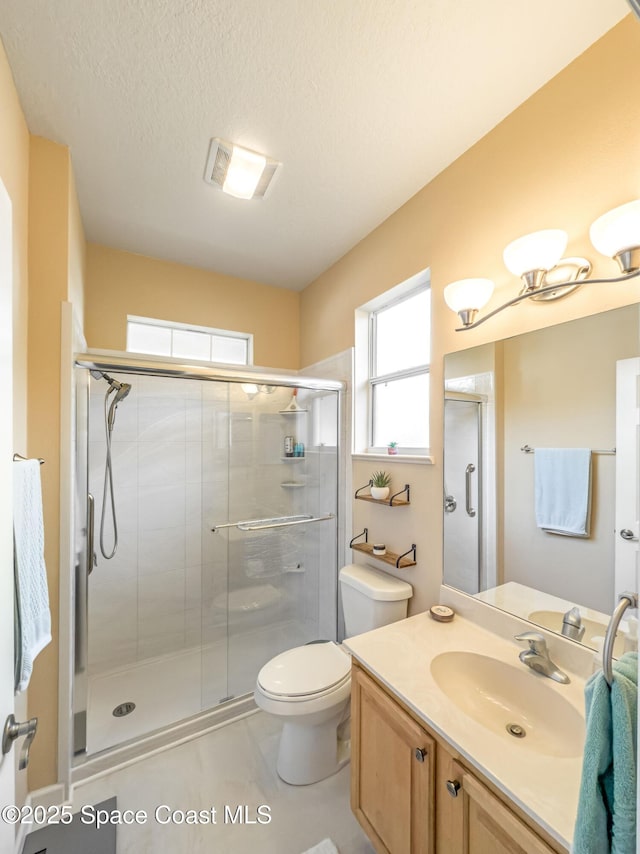 bathroom with vanity, a textured ceiling, toilet, and walk in shower