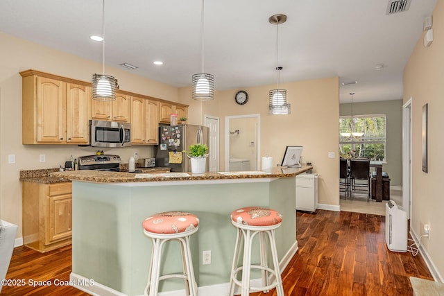 kitchen with light brown cabinetry, appliances with stainless steel finishes, dark hardwood / wood-style flooring, pendant lighting, and a center island