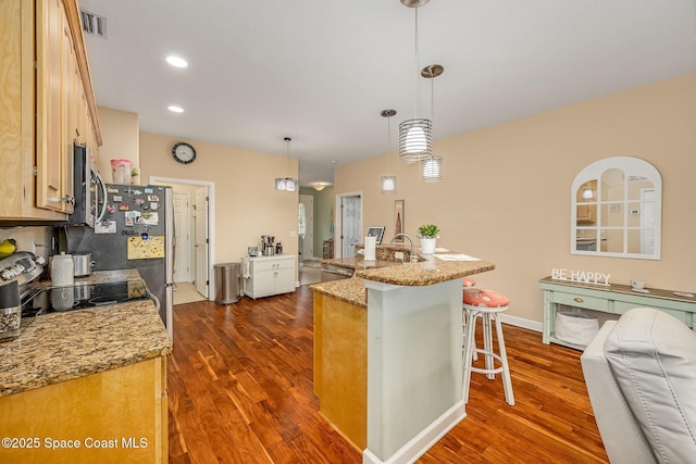 kitchen with a breakfast bar, sink, light stone countertops, and hanging light fixtures