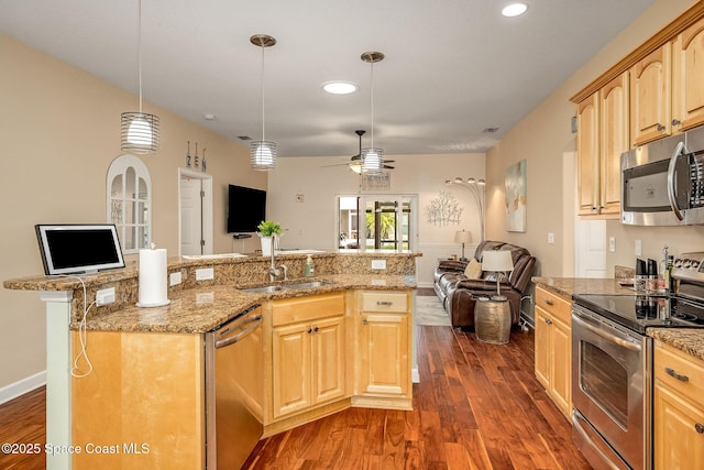 kitchen with ceiling fan, sink, hanging light fixtures, stainless steel appliances, and a kitchen island with sink