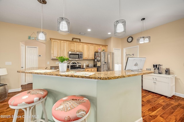 kitchen featuring pendant lighting, dark hardwood / wood-style flooring, stainless steel appliances, and a center island with sink