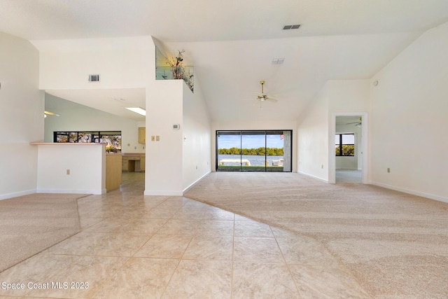 unfurnished living room with ceiling fan, light tile patterned flooring, and a high ceiling