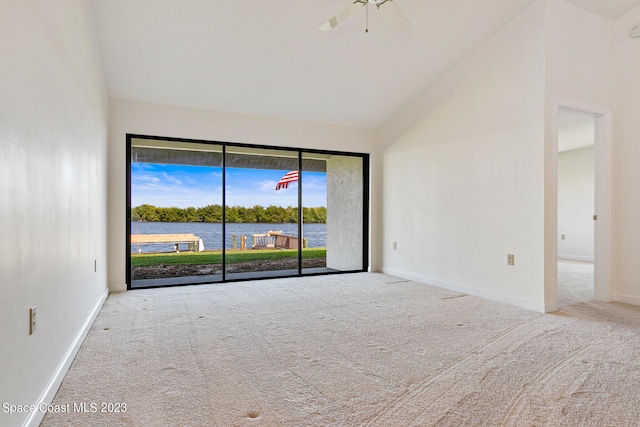 unfurnished room featuring ceiling fan, a water view, light carpet, and vaulted ceiling