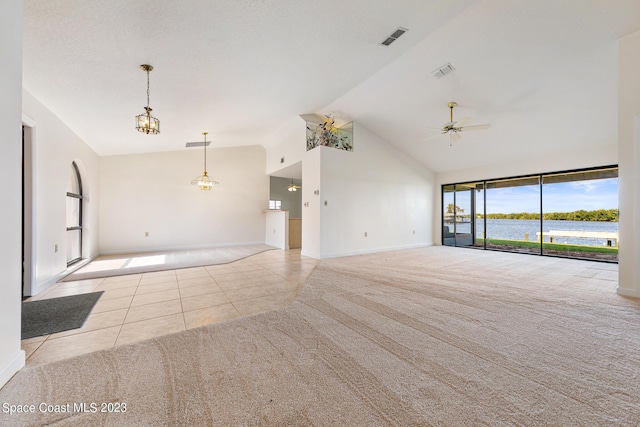 unfurnished living room with light tile patterned floors, ceiling fan with notable chandelier, a water view, and vaulted ceiling