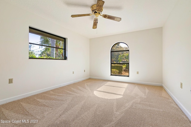 carpeted spare room with ceiling fan and plenty of natural light