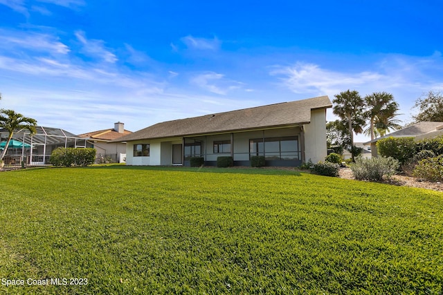 back of property with a lawn and glass enclosure