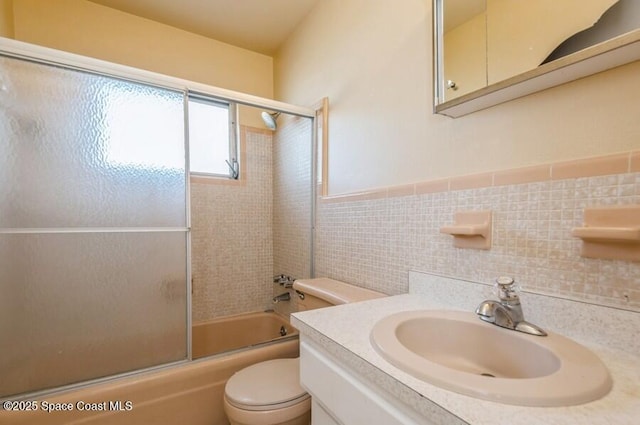 full bathroom featuring vanity, toilet, tile walls, and enclosed tub / shower combo