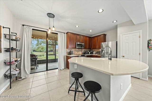 kitchen featuring light tile patterned floors, appliances with stainless steel finishes, pendant lighting, and tasteful backsplash