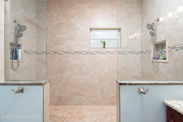 bathroom with a tile shower and vanity