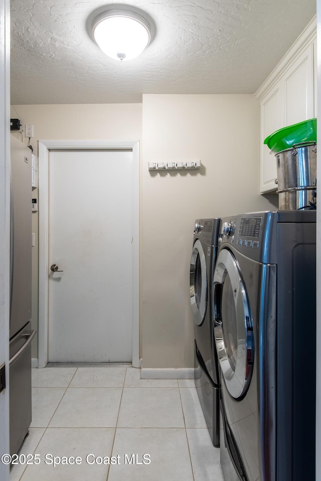 washroom with light tile patterned flooring, cabinets, separate washer and dryer, and a textured ceiling