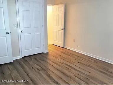 unfurnished bedroom with dark hardwood / wood-style flooring and a closet