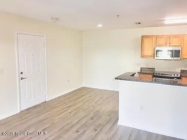 kitchen featuring light brown cabinetry, stove, and light wood-type flooring