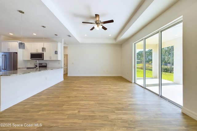 kitchen featuring stone counters, decorative light fixtures, white cabinetry, and appliances with stainless steel finishes