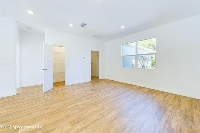 unfurnished bedroom with a spacious closet, light wood-type flooring, and a closet