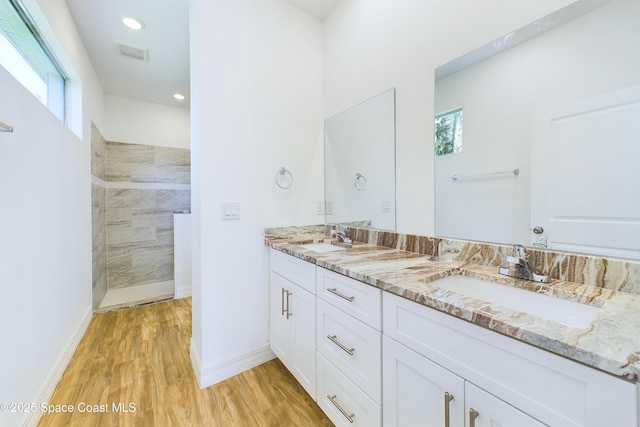 bathroom featuring a tile shower, vanity, hardwood / wood-style flooring, and a healthy amount of sunlight