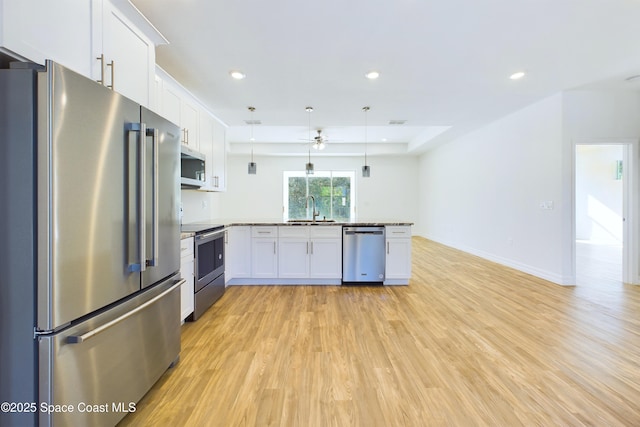 kitchen featuring sink, stainless steel appliances, kitchen peninsula, decorative light fixtures, and white cabinets