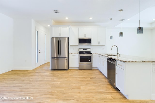 kitchen featuring light stone countertops, sink, pendant lighting, white cabinets, and appliances with stainless steel finishes