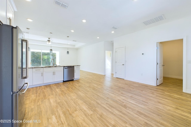 kitchen featuring light wood-type flooring, stainless steel appliances, ceiling fan, sink, and white cabinetry