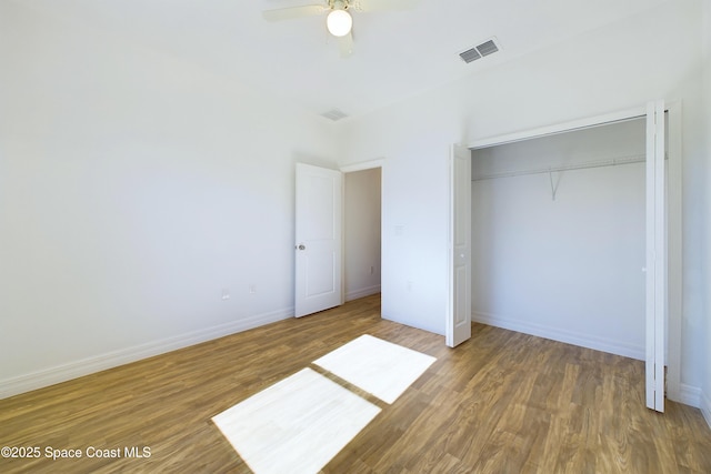 unfurnished bedroom featuring hardwood / wood-style floors, a closet, and ceiling fan