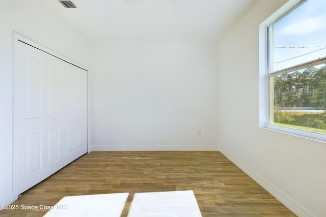 unfurnished bedroom featuring a closet, dark hardwood / wood-style flooring, and multiple windows