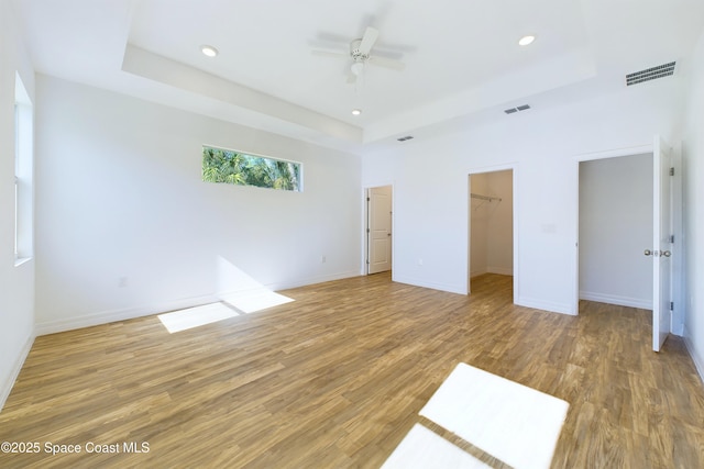 interior space featuring ceiling fan, a raised ceiling, a spacious closet, and a closet