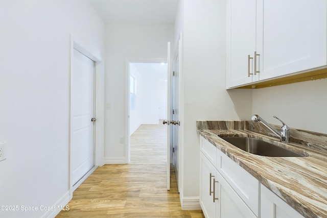 kitchen with white cabinets, light hardwood / wood-style flooring, and sink