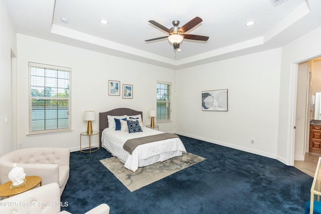 carpeted bedroom featuring ceiling fan and a raised ceiling