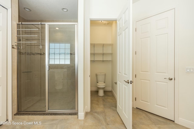 bathroom with tile patterned floors, toilet, and a shower with shower door