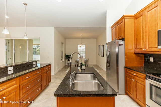 kitchen with dark stone countertops, a kitchen island with sink, pendant lighting, and stainless steel refrigerator with ice dispenser