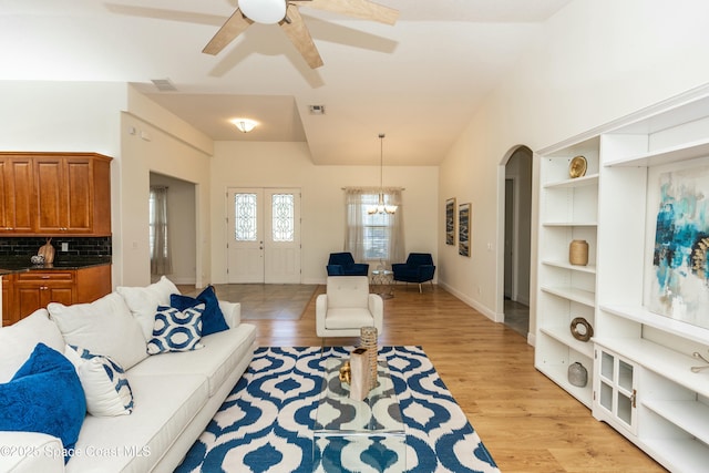 living room featuring ceiling fan with notable chandelier and light hardwood / wood-style floors