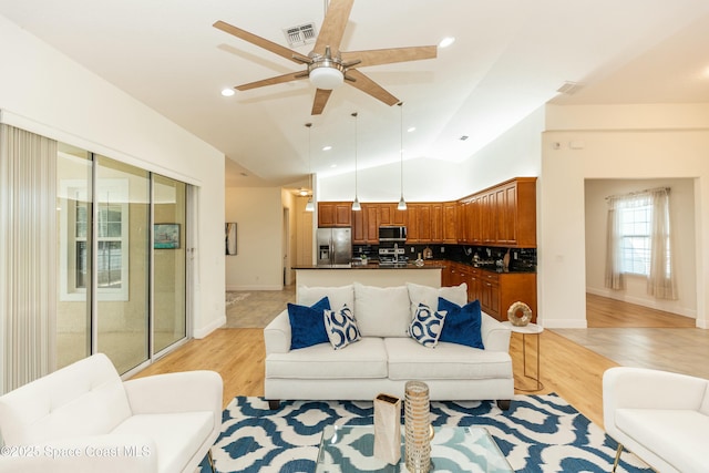 living room featuring light hardwood / wood-style floors, vaulted ceiling, and ceiling fan