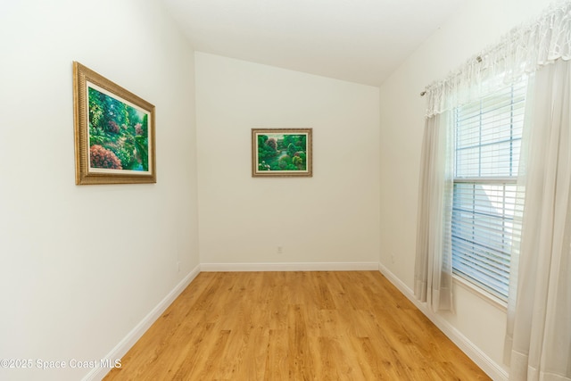 unfurnished room featuring light hardwood / wood-style floors and lofted ceiling