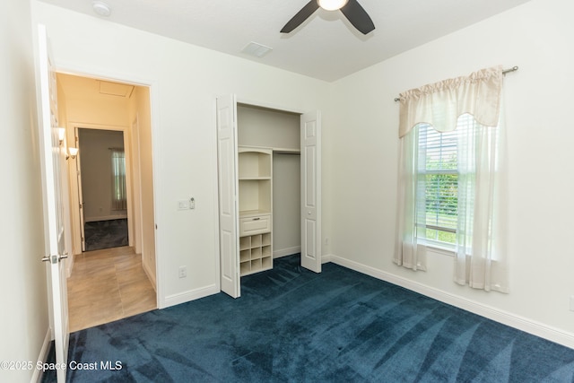 unfurnished bedroom with ceiling fan, dark carpet, and a closet