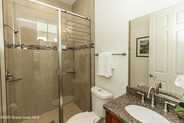 bathroom featuring vanity, toilet, and a shower with shower door