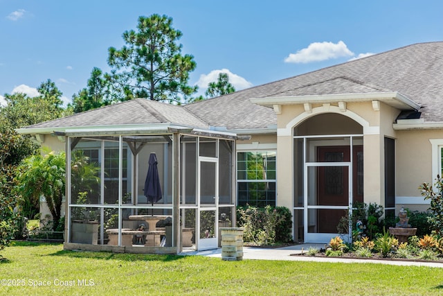 rear view of property featuring a sunroom and a lawn