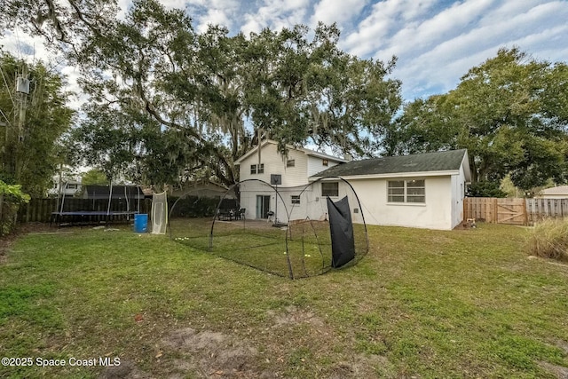 back of house with a lawn and a trampoline