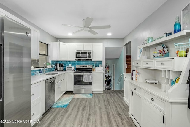 kitchen featuring ceiling fan, stainless steel appliances, tasteful backsplash, white cabinets, and sink