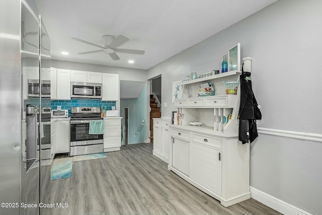 kitchen featuring white cabinetry, light hardwood / wood-style floors, ceiling fan, stainless steel appliances, and tasteful backsplash