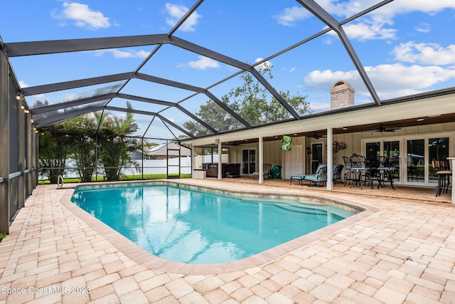 view of pool featuring glass enclosure, ceiling fan, and a patio