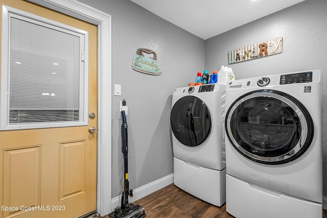 clothes washing area featuring dark hardwood / wood-style flooring and washer and clothes dryer