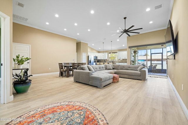 living room featuring ceiling fan, light hardwood / wood-style flooring, vaulted ceiling, and ornamental molding