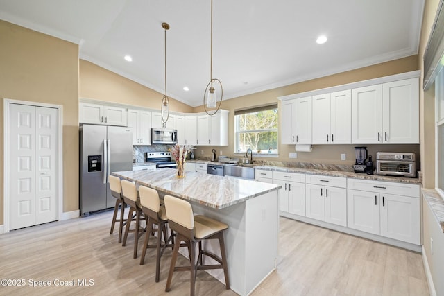 kitchen with stainless steel appliances, white cabinetry, hanging light fixtures, and an island with sink