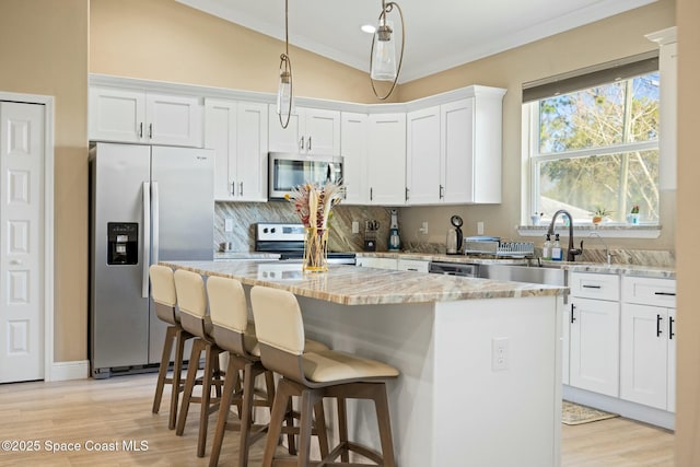 kitchen featuring light stone countertops, appliances with stainless steel finishes, vaulted ceiling, white cabinets, and a center island