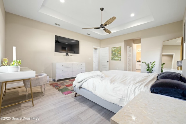 bedroom featuring a raised ceiling, ceiling fan, and light hardwood / wood-style flooring