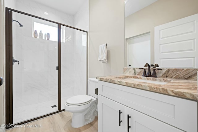 bathroom featuring hardwood / wood-style floors, vanity, toilet, and an enclosed shower